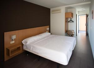 马德里Hostal Mediterranea的卧室配有一张白色大床和木制床头板