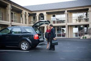基督城萨勒诺汽车旅馆公寓的男人和女人站在汽车旁边,车厢开