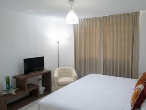 危地马拉In & Out Hotel的酒店客房带一张床、一台电视和一把椅子