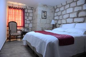 拿撒勒门萨克里斯提旅馆的一间卧室设有一张大床和石墙