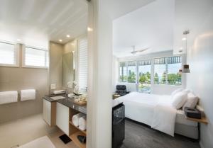 埃尔利海滩降灵岛中心酒店的白色的卧室设有一张大床和一间浴室。