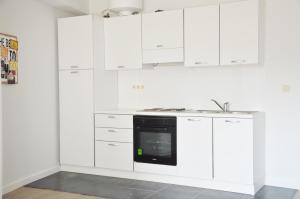 布鲁塞尔大广场附近辛巴公寓的白色的厨房配有白色橱柜和黑烤箱