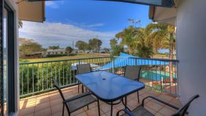 帝坎湾海豚沃特酒店的一个带桌椅的阳台和一个游泳池