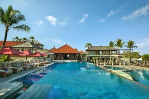 勒吉安巴厘尼克莎玛海滩精品度假酒店的度假村的游泳池,配有椅子和遮阳伞