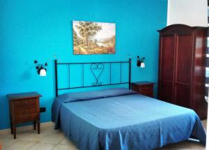 圣维托罗卡波Mariposa B&B的一间卧室设有蓝色的墙壁和一张带蓝色床单的床