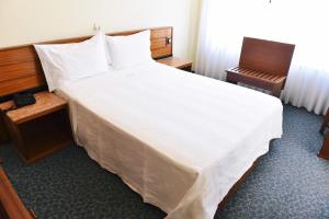 马亚机场酒店的一张大白色的床,位于酒店客房内