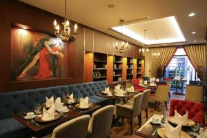 顺化斯嘉丽精品酒店的餐厅设有桌椅,墙上挂有绘画作品