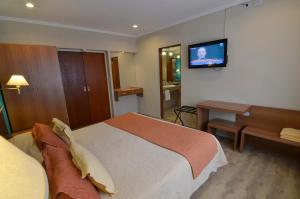 特尔马斯德里奥翁多Alto Verde Suite & Apart的卧室配有一张床,墙上配有电视。