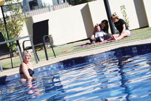 天鹅山蓝花楹汽车旅馆的和家人一起坐在游泳池里的女人