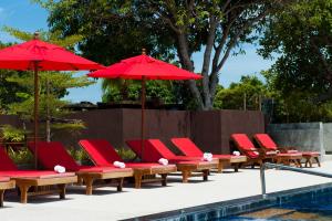 Haad Chao Phao哈德朝宝海上花园度假酒店的游泳池旁的一排红色躺椅和遮阳伞