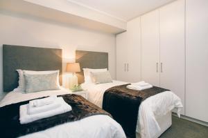 开普敦Superior Apartment Mayfair的一间卧室配有两张带毛巾的床