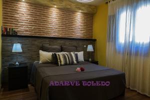 托莱多托莱多阿达勒维公寓酒店的一间卧室设有一张带砖墙的大床