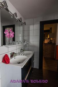 托莱多托莱多阿达勒维公寓酒店的浴室设有2个水槽、镜子和粉红色的鲜花