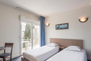 昂蒂布Appart'City Classic Antibes的酒店客房设有两张床和窗户。