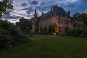 圣帕泰讷圣帕特纳城堡酒店的黄昏时有草地庭院的古老豪宅