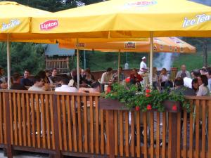 斯米扎尼Park Hotel Čingov的一群人坐在餐厅里,在黄伞下