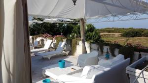 罗萨玛里纳Villa Rosamarina的庭院配有白色的椅子和遮阳伞。
