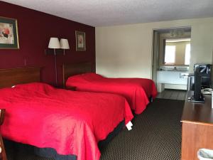 梅里尔维尔FairBridge Inn Express Merrillville的两张位于酒店客房的床铺,配有红色床单