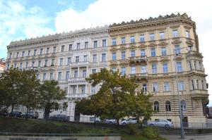 布拉格瓦伦蒂娜旅舍的一座白色的大建筑,前面有汽车停放