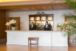 安约马奇Hotel Grand Tiara Minaminagoya的两名妇女站在酒店大堂的柜台