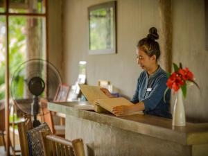 琅勃拉邦梦中精品度假村的坐在柜台上读书的女人