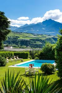 拉古多Pension Morenfeld的一个带桌椅的游泳池,背景是群山