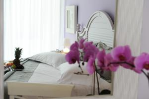 米克罗斯雅洛斯圣尼古拉斯度假酒店的一间卧室配有一张带镜子和紫色鲜花的床