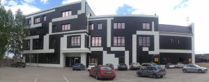 克麦罗沃Sport Hotel Maximum的一座黑白的建筑,停车场内有汽车停放
