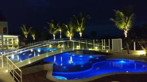 瓜拉图巴Kaakupe Praia Hotel的一座游泳池,晚上有一座桥在上面