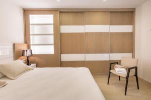 阿吉内金海滩Arguineguín Bay Apartments的卧室配有白色的床和椅子