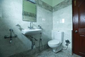 乌提Tulips Valley View Resorts的一间带水槽、卫生间和镜子的浴室