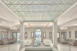 佩里萨水蓝色海滩酒店的大堂设有白色的桌椅和天花板。