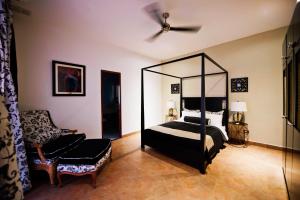 巴拿马城La Isabela Suites的一间卧室配有一张天蓬床和一把椅子