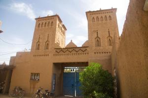 斯库拉Gite Kasbah La Palmeraie的一座建筑,有两座塔楼和一扇蓝色的门