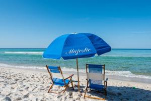巴拿马城海滩Majestic Beach Resort, Panama City Beach, Fl的海滩上的两把椅子和一把遮阳伞