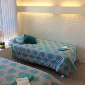 梅林布拉科莫公寓的一间卧室配有两张带蓝色和绿色床单的床