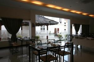帝力拉姆劳酒店的餐厅设有桌椅和大窗户。