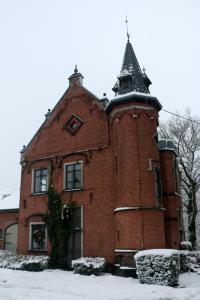 斯帕Un Air de Château的一座旧砖砌的建筑,有一座塔楼,下雪
