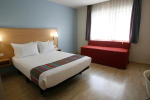马德里托里拉古纳旅程住宿酒店的酒店客房设有一张大床和一张红色长凳