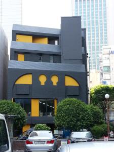 釜山斯里旅馆的一座黑色和黄色的建筑,前面有汽车停放