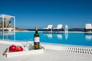 纳乌萨Villa Irini的游泳池旁的一瓶葡萄酒和玻璃杯