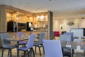 卢德南南锡 - 卢德斯基里亚德酒店的餐厅设有木桌和蓝色椅子