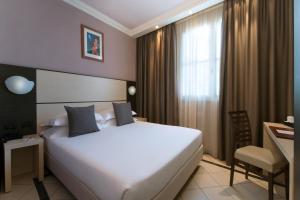 斯培西亚斯佩齐亚CDH酒店的酒店客房设有一张白色大床和一张书桌