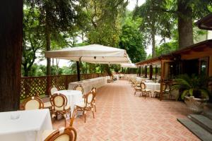 阿里恰Hotel Villa Aricia的一个带桌椅和遮阳伞的户外庭院。