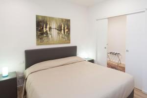维琴察康体家园公寓的卧室配有白色的床和墙上的绘画作品