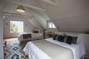 RalúnMareas Ralun Lodge的阁楼卧室设有两张床和窗户。