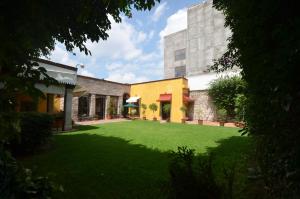 莫雷利亚卡勒里拉莫雷利亚豪生国际酒店的一座建筑前的庭院,上面有绿色草坪