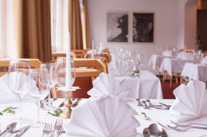 耶岑斯阿尔彭弗雷德酒店的用餐室配有带玻璃杯和餐巾的白色桌子