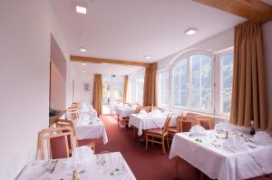 耶岑斯阿尔彭弗雷德酒店的餐厅设有白色的桌椅和窗户。