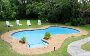 伊丽莎白港African Aquila Guest Lodge的一个带椅子和桌子的大型游泳池